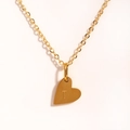 Vue macro détaillée d'un collier pendentif coeur doré gravé avec la lettre T personnalisée - Lettre T