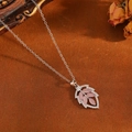 Detailed close-up of leaf pendant with pink opal and crystals on vintage background - Silver Pink Stone Leaf Necklace