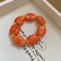 Detailed macro of orange marble acrylic oval beads with golden metal spacers - Orange