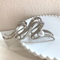 Elegant silver metal flower hair claw with pearl accent on a decorative ceramic plate - Silver Pearl Style