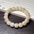 White Bodhi seed bracelet with golden celestial engravings on dark wood background - Sun Moon Star