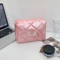 Detailansicht der rosa gesteppten Kosmetiktasche mit Webetikett auf einem Schreibtisch - Rosa