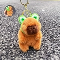 Brown capybara plush keychain wearing green frog hat with golden metal clasp accessory - Frog Headwear