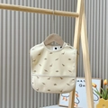 Waterproof beige baby bib with brown dinosaur prints and adjustable neck snaps - Dinosaur Paradise