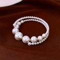 Detail van meerlaagse witte parelarmband met gouden kralen op donkere stof - Parel Kralen Open Armband
