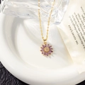 Detail of a golden necklace with a purple petal pendant on a white ceramic plate - Necklace (with Lips Chain) / Purple