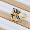 Dettaglio ravvicinato di un anello a forma di orsetto dorato con pietre di zircone blu - Blu scuro