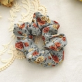 Detailed macro view of a light blue floral scrunchie with warm orange rose patterns - Blue