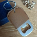 Close-up of stainless steel bottle opener keychain with brown PU leather on wood surface - Large / Brown
