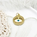 Detailed macro view of a gold evil eye charm with blue enamel on white lace background - White Eye Round Disc 22.5*18.7mm