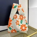 Chic knitted floral tote bag with orange flowers on a white base in a golden tray - Orange Daisy