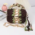 Detail of handmade crochet shoulder bag with colorful fabric tassel and metal chain - Coffee