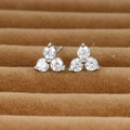 Macro shot of silver three-stone stud earrings set in brown velvet jewelry box - Silver / White Zirconia