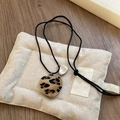 Detailed view of leopard print heart pendant on woven rope with silver engraved charm - Brown