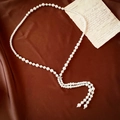 Detalle de collar largo de perlas con borla de diamante sobre fondo de seda - Collar Largo de Borlas de Perlas Blancas / Blanco