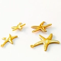 Set of four gold starfish hollow pendants in various sizes with integrated hanging rings - Gold