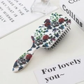 Detail of white hairbrush with skull and rose patterns on a desk with props - Skull and Rose