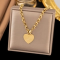 Gold stainless steel heart necklace with sunburst texture on beige jewelry box - Ray Heart / Gold