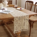 Gros plan détaillé du chemin de table beige au crochet avec motifs floraux et pompons - 30x240cm / Style Crochet Trèfle
