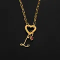Gold heart-shaped clasp necklace with letter L charm and pink stone detail. - L