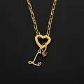 Gold heart-shaped clasp necklace with letter L charm and pink stone detail. - L