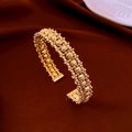 Golden double-layer gourd bangle with textured bead rows on red velvet background - Gold Beaded Pave Open Bangle