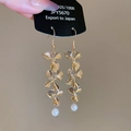 Detailed macro view of gold-tone metal flower earrings with pearl tassels and hook design - Ear Hook - Gold Flower