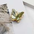 Detail of a vintage golden butterfly hair claw clip with green marbled wing accents - Dark Green