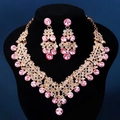 Makroaufnahme einer V-förmigen Goldhalskette mit rosa Strasssteinen auf Samtständer - Gold Rosa Zirkonia