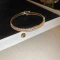 Macro detail of gold double-row rhinestone spiral bangle in luxury jewelry gift box - Style 2 / Gold