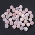 Polished light pink rose quartz crystal spheres displayed on a deep black background - Rose Quartz