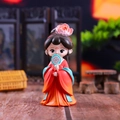 Detail view of cute Chinese doll in orange Hanfu holding a fan with a blurred background - Jade Brown Blue