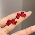 Close-up of matte red bow stud earrings held in hand to show the small delicate size - 44# Steel Needle - Red - Bow