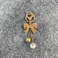 Porte-clés doré avec nœud en strass marron et perle ornée d'un camélia noir - Nouveau Champagne