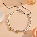 Detail of bohemian shell necklace with gold starfish and moon charms on a woven cord - Black Rope Starfish Necklace