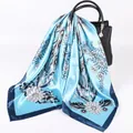 Sciarpa in raso blu con stampa floreale bianca drappeggiata su una borsa in pelle nera - Blu