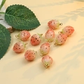 Primo piano di dieci ciondoli a fragola in resina con ganci dorati su fondo giallo - Forma di fragola / 11*19mm 1 Pezzo / Arancione