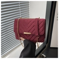 Detail of burgundy suede chain bag showing V-shaped quilted texture and gold hardware - Red