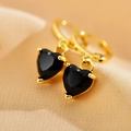 Detail of golden hoop earring with a black heart-shaped pendant on soft fabric - Black