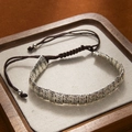 Macro view of retro carved silver metal cylinders with S-pattern on brown braided rope - 28 S-Pattern Cylinders Bracelet