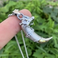 Polished silver dragon tooth pendant necklace held outdoors with textured metal detail - Silver All-Metal Style