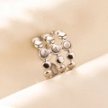Macro shot of a triple-row beaded silver steel ring on textured silk fabric - Triple Layer Beaded / Silver White
