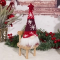 Dettaglio di uno gnomo natalizio seduto su una sedia di legno con decorazioni festive - Uomo della Foresta Seduto / Rosso
