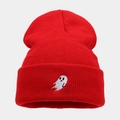 Macro detail of red knitted beanie featuring a white ghost embroidery on the cuff fold - Red