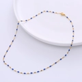 Detailansicht der 18k vergoldeten Kette mit blauen Emaille-Anhängern auf Keramikteller - Gold + Blau Emaille