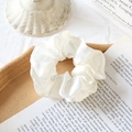 Elegant pearl white satin scrunchie with soft sheen displayed on a wooden tray - Off White
