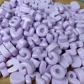 Dettaglio di piccole perline alfabetiche in resina viola chiaro per creazioni fai-da-te - Dolcetto o Scherzetto / Confezione singola casuale / Viola