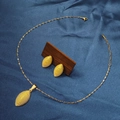 Golden textured oval leaf necklace and earring set displayed on elegant blue silk fabric - E6107-10/Gold Textured Leaf