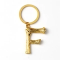 Detailed macro shot of a golden letter F keychain with a unique bamboo texture design - Letter F