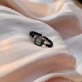 Macro-detail van een zwarte kralenring met een katvormige steen op zachte beige zijde - One Size(Elastisch) / Kattenkop Parelmoer Zwarte Spinel Ring